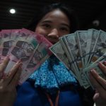 Karyawan menunjukkan uang pecahan rupiah dan dolar Amerika Serikat (AS) di gerai penukaran mata uang asing Haji La Tunrung, Makassar, Sulawesi Selatan, Rabu (20/5/2026).