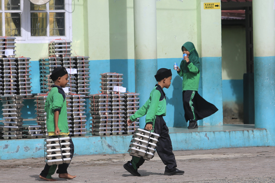 Sejumlah siswa membawa ompreng Makan Bergizi Gratis (MBG) di komplek Madrasah Ibtidayyah Negeri (MIN) 11 Aceh Barat dan Madrasah Tsanawiyah Swasta (MTS) Harapan Bangsa Desa Kuta Padang, Johan Pahlawan, Aceh Barat, Aceh, Rabu (20/5/2026)