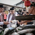 Gubernur DKI Jakarta Pramono Anung (kiri) didampingi Ketua Dewan Adat Majelis Kaum Betawi Fauzi Bowo (kedua kiri) berbincang dengan penjual ikan bandeng pada Festival Bandeng Rawa Belong 2026 di Jakarta, Sabtu (14/2/2026).