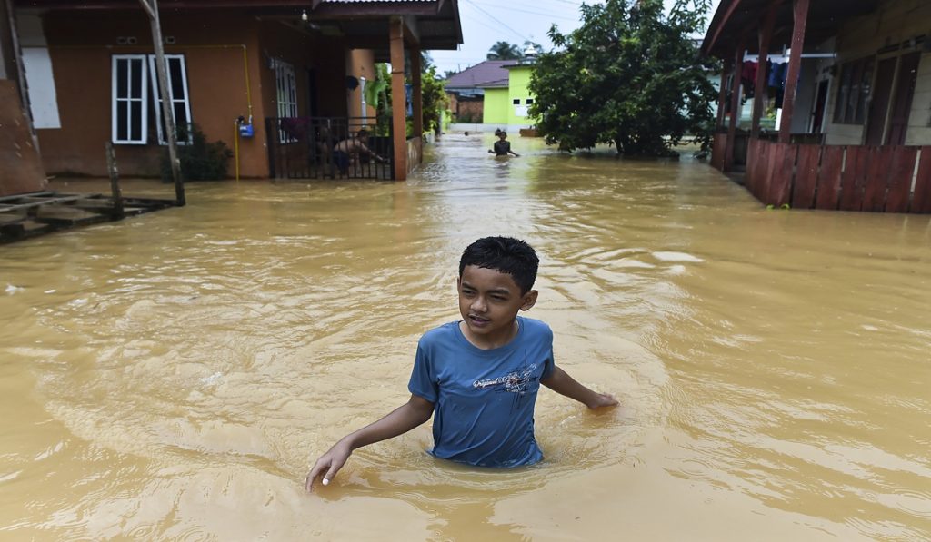 Seorang anak menerobos jalan kawasan permukiman yang terendam banjir di Kenali Asam Bawah, Kota Baru, Jambi, Kamis (18/6/2026).