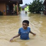 Seorang anak menerobos jalan kawasan permukiman yang terendam banjir di Kenali Asam Bawah, Kota Baru, Jambi, Kamis (18/6/2026).